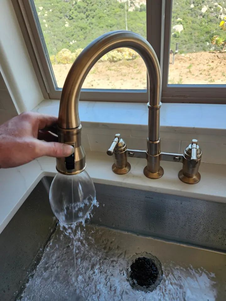 Water flowing from a kitchen faucet during a fixture check